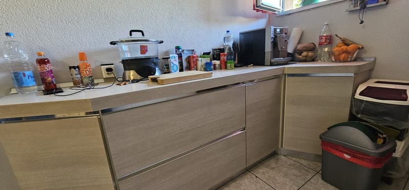 modern kitchen with wooden countertops, built-in appliances, and a trash bin