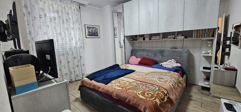 Bedroom with bed, desk, monitor, cabinet, shelves, picture frame, curtain, trophy, mirror