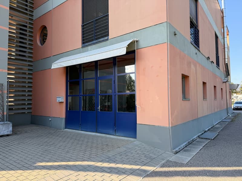 A building with double glass doors, large windows, a white awning, a round window, and brick walls.