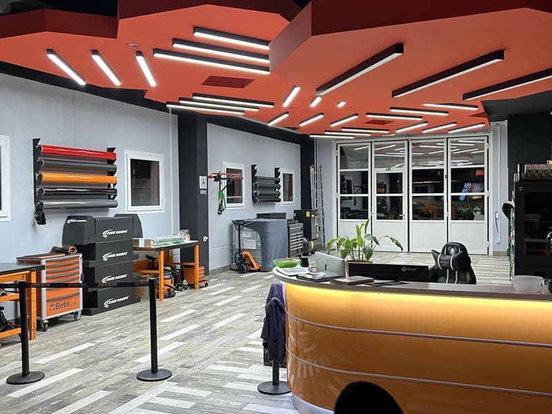 shopfront, orange desk, plants, tools, orange ceiling lights, trolley, filing cabinet