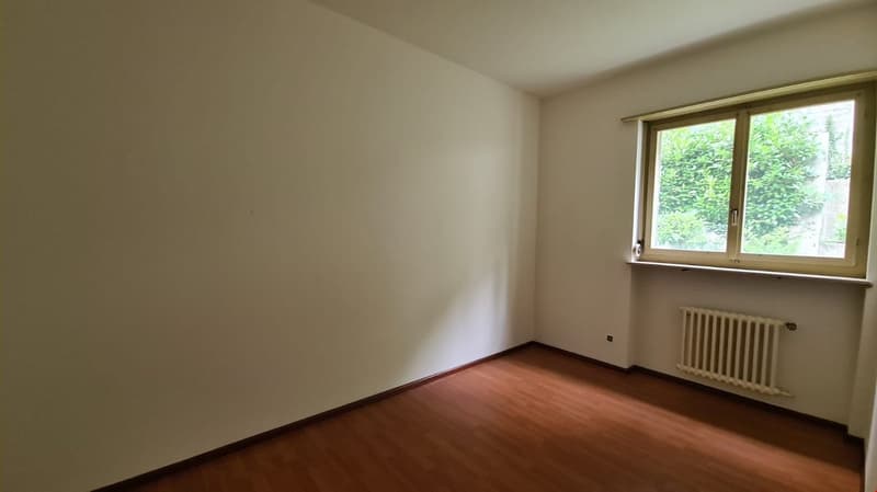 Empty room, wooden floor, white walls, large window, radiator on the wall, power outlet