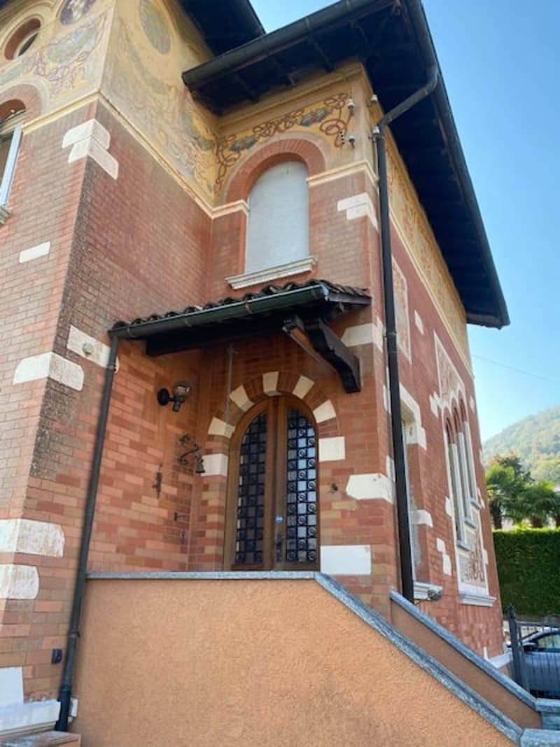 red brick facade, main entrance with awning, white painted window frames, steps leading to entrance