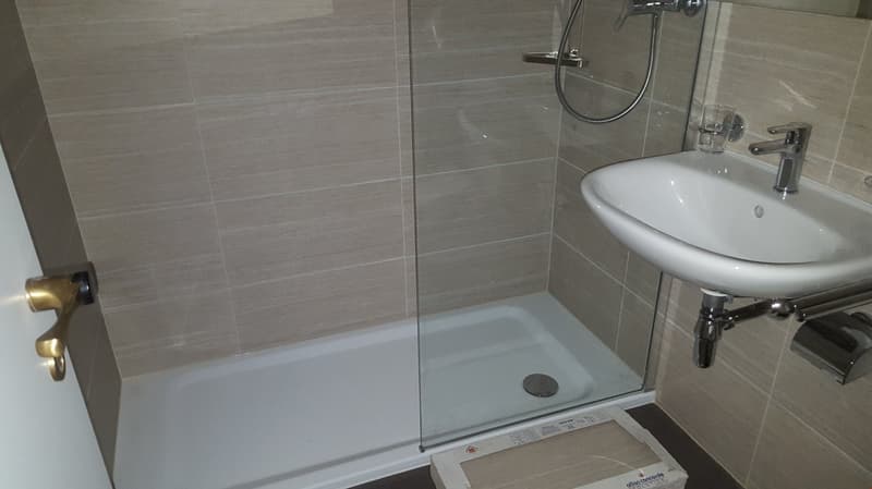 shower area, white sink, tiled walls and floor, brass shower head, white door