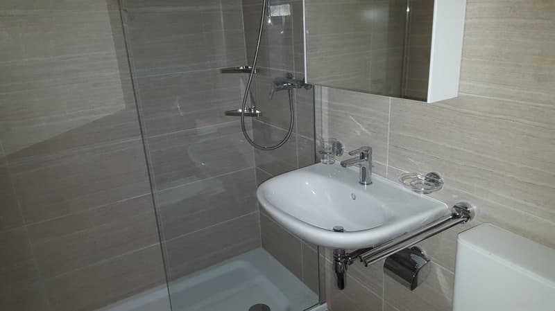 modern bathroom with shower, toilet, wash basin, glass shower door, beige tiles, white fixtures