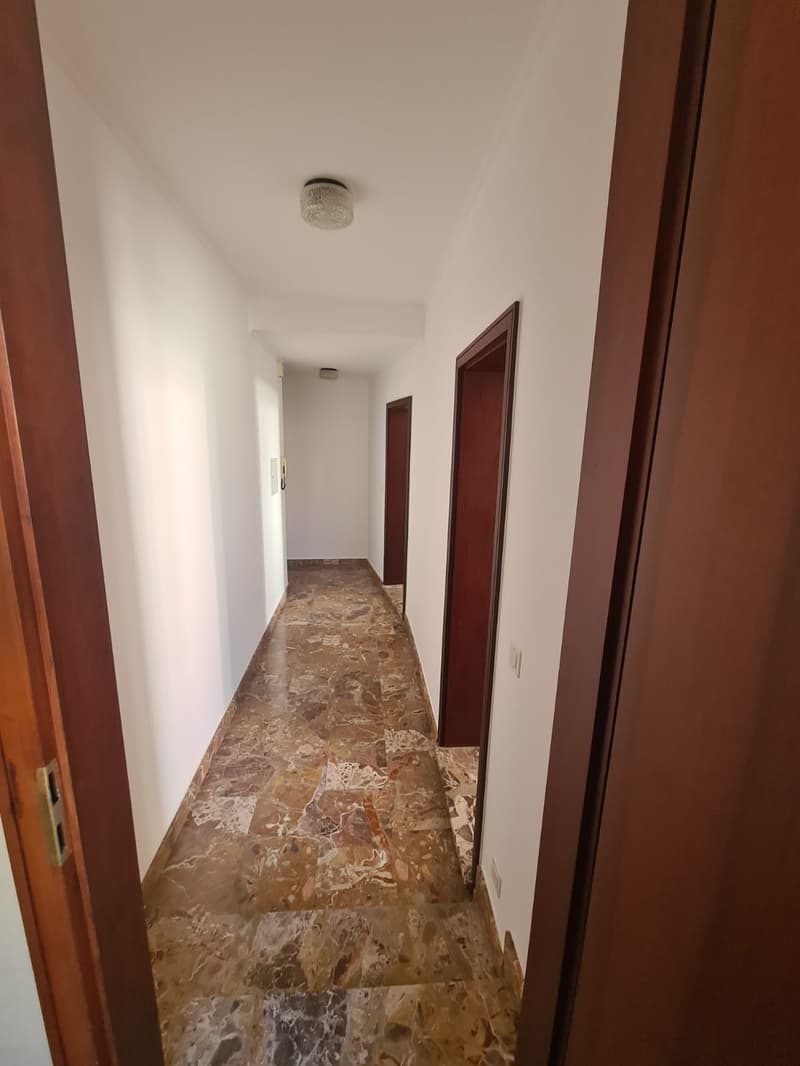 tiled hallway, white walls, wooden doors, light fixtures