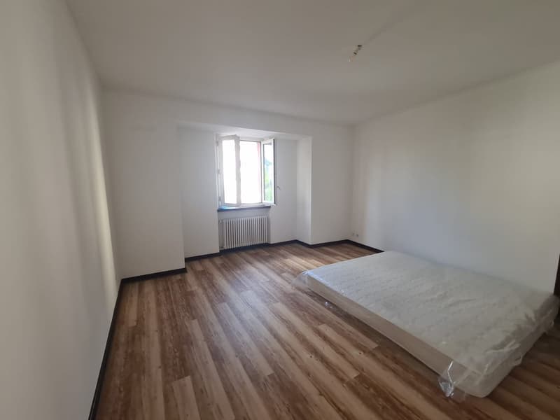 Empty room, white walls, wooden floors, radiator, window, bed