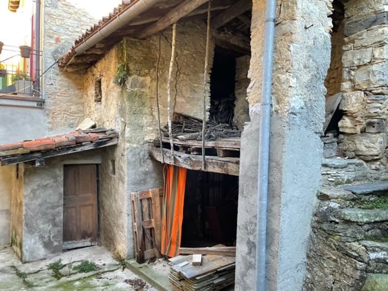 Old stone house, damaged door, rusty beams, wooden door, piles of wood inside