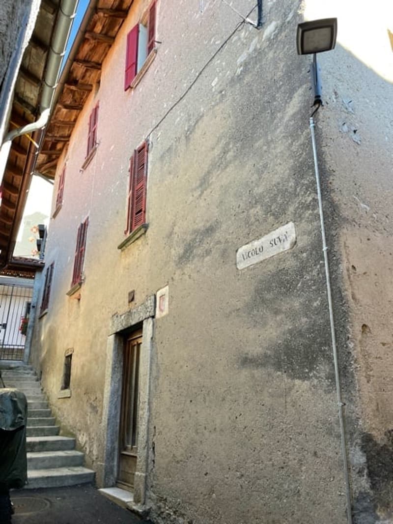 Old building with stucco and red shutters. Stairs leading up to the entrance.