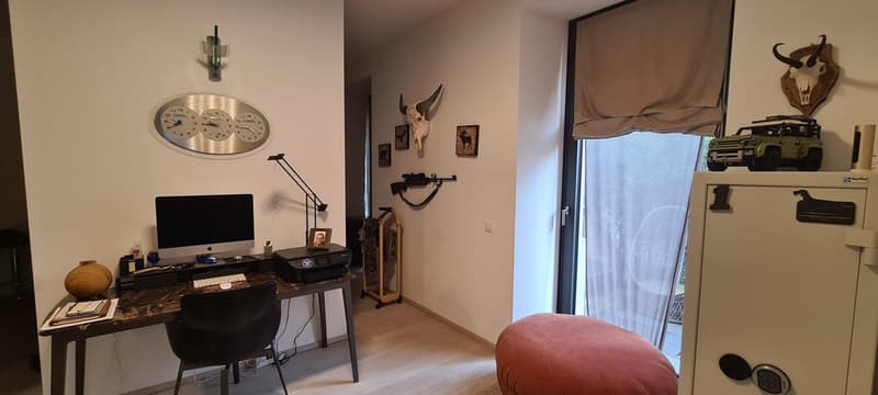 Office with desk, computer, keyboard, mouse, lamp, clock, frame, stool, rug, gun, picture, pillow, window, white curtains, wardrobe