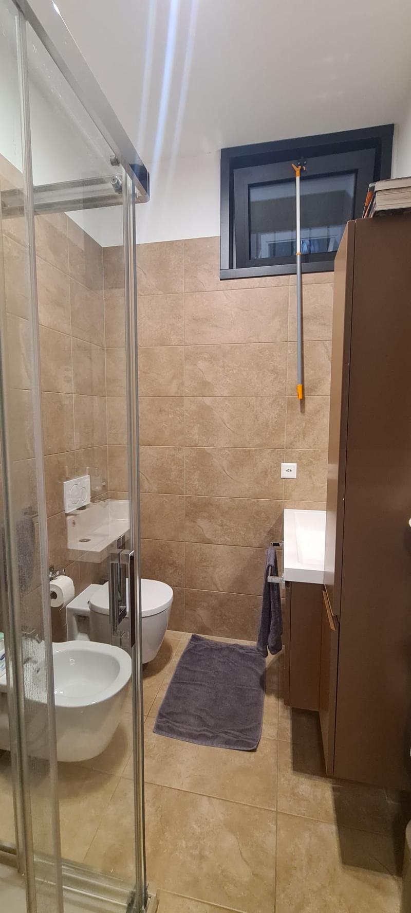 Bathroom: Tiled walls, Tiled floor, Shower enclosure, sink, toilet, cabinet, rug, toilet paper holder, towels