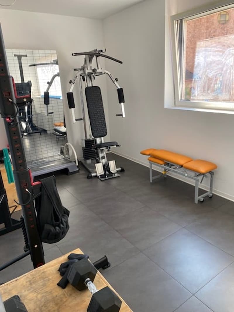 Home gym with various equipment, including a weight bench, treadmill, and dumbbells.