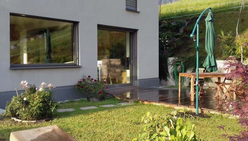 white house, large windows, wooden deck, outdoor table, green umbrella, garden, plants