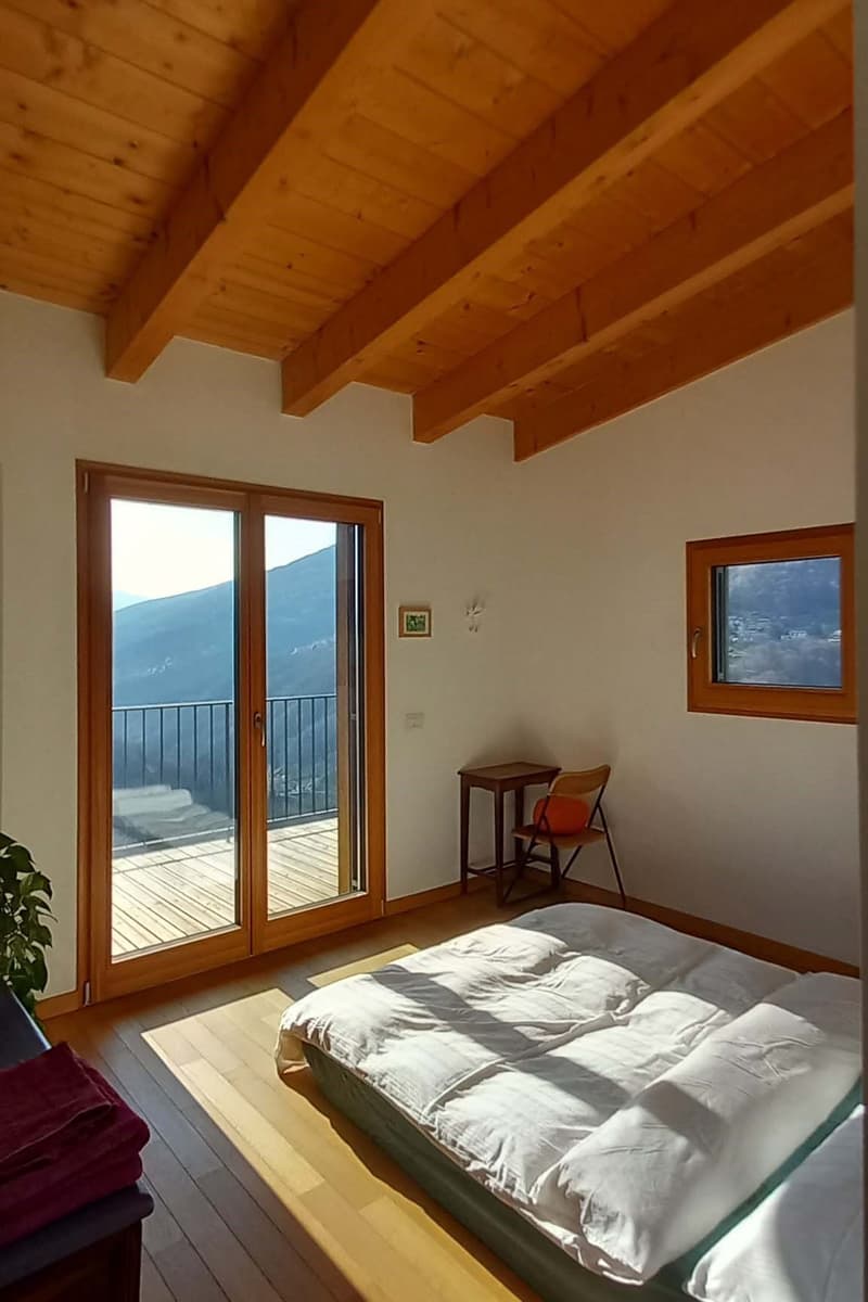 bedroom with wooden floor, wooden ceiling, sliding glass doors, balcony, bed, chair, table, picture frame, plant