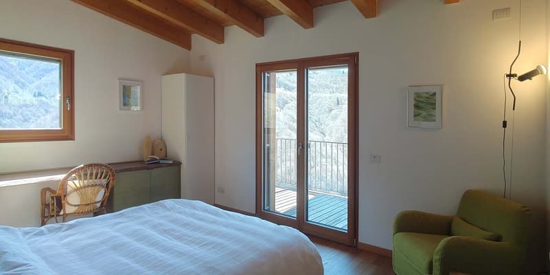 bedroom with bed, chair, cabinet, sliding glass door to balcony, wooden ceiling, picture frames, lamp
