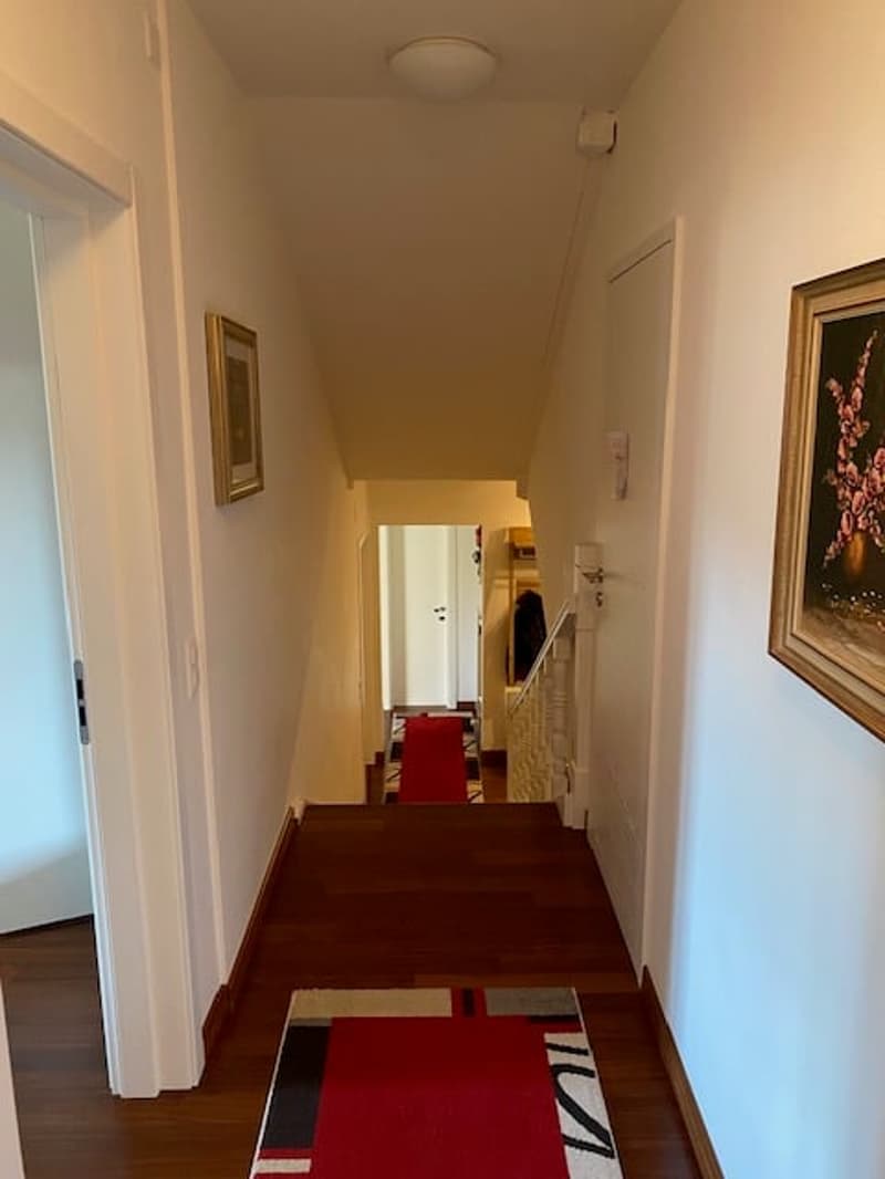 wooden floor, white walls, red carpets, picture frames, ceiling light