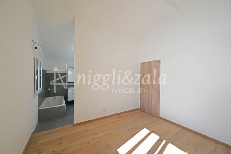 Bathroom with bathtub, wooden door, white walls, wooden floor, window