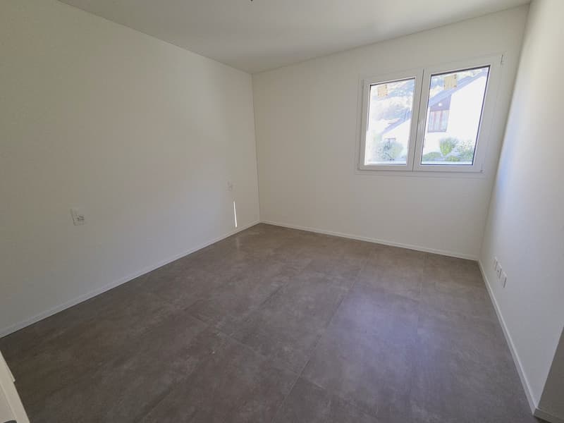 Empty room with white walls, gray tiled floor, a window with white frames.