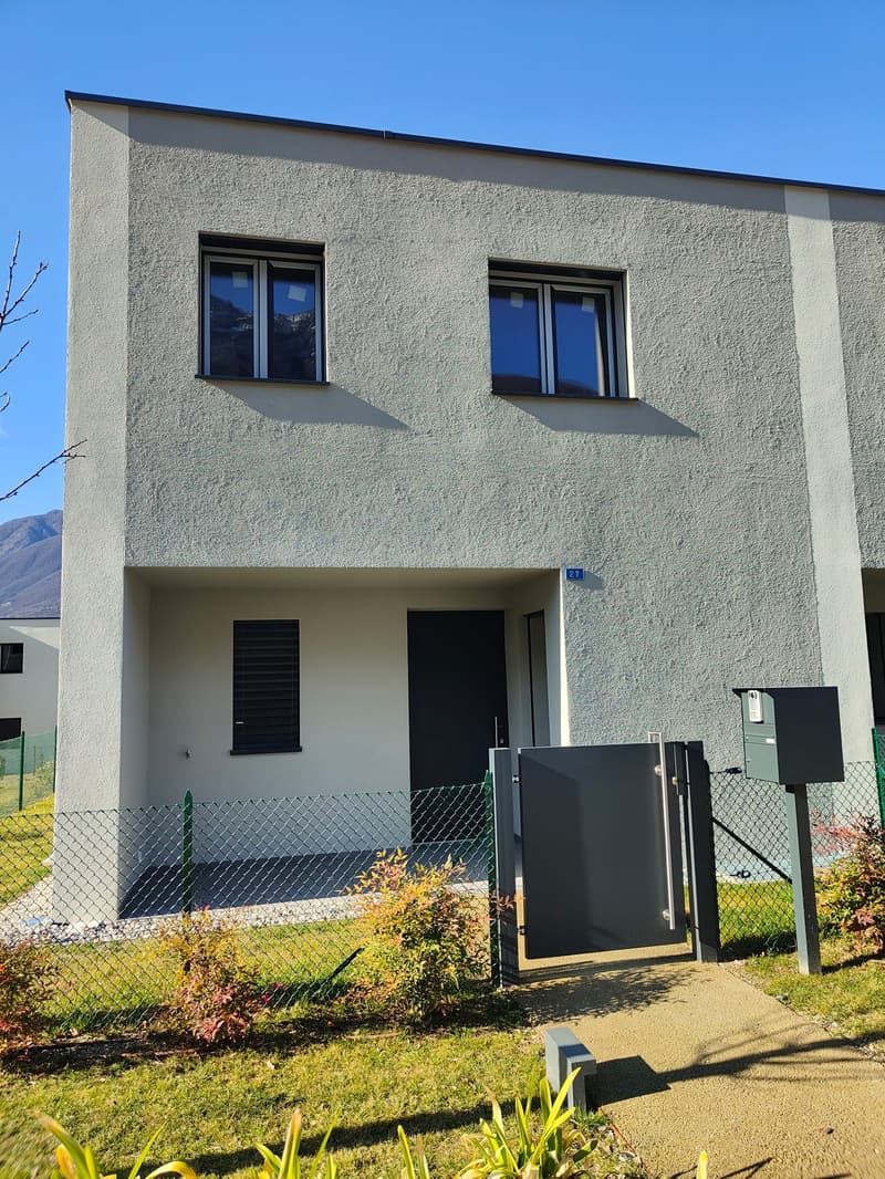 2-story building, white walls, large windows, gray shutters, garden, gate, gray mailbox, gravel driveway