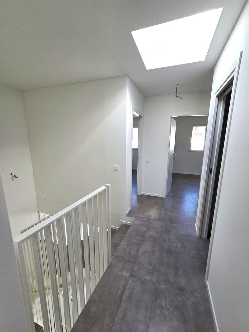 Staircase, hallway, white walls, gray floor, skylight, white railing