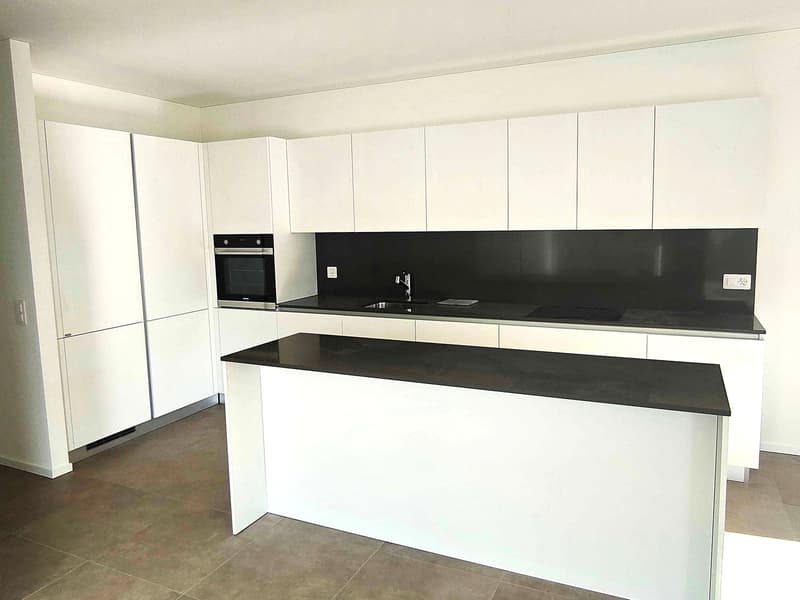 modern white kitchen with black granite countertops, white cabinets, stainless steel oven, sink with faucet, island, tiled floor