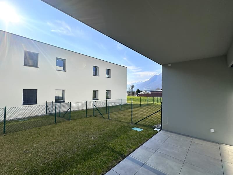2-story apartment building with white exterior, large windows, fenced yard with grass, and a covered patio or balcony area