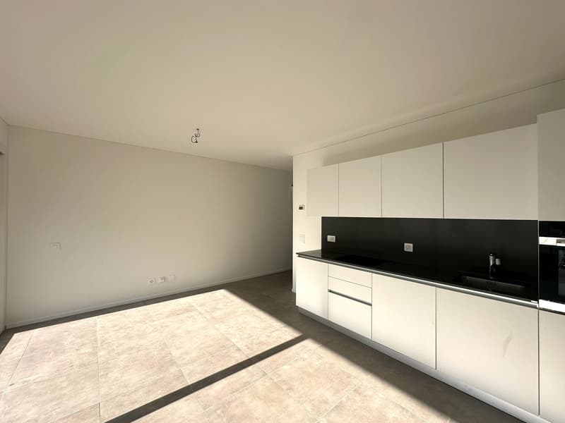 Spacious kitchen with white cabinets, black countertop, and tile flooring. Dishwasher is visible.