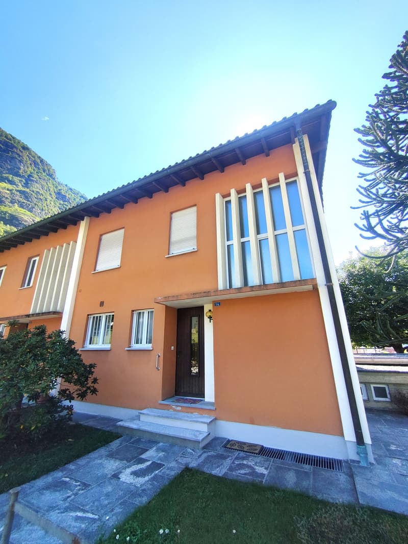 2-story orange house with large windows, balcony, and stone patio in front of the house