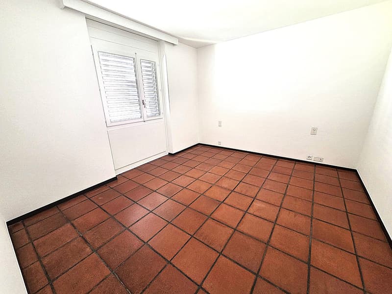 empty room, white walls, brown tiles, window with shutters, power outlets