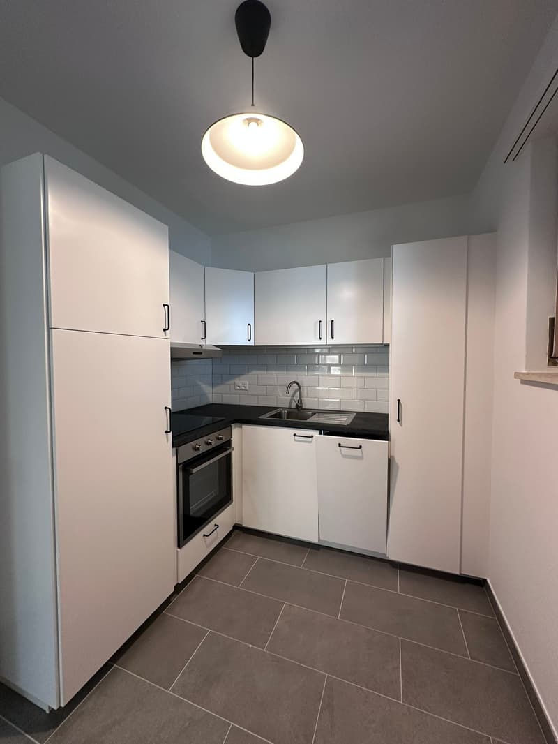 modern kitchen with white cabinets, black countertops, integrated oven, dishwasher, sink, and faucet