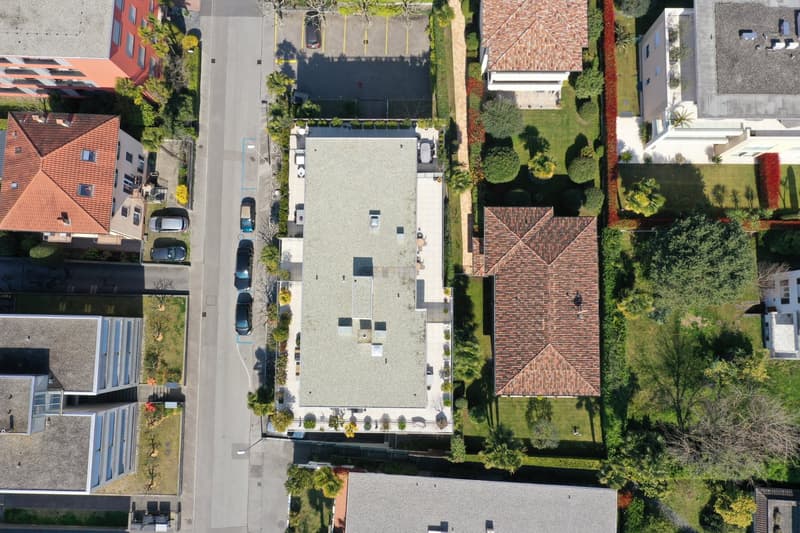 Aerial view of a residential area with multiple buildings, a parking lot, and a street.