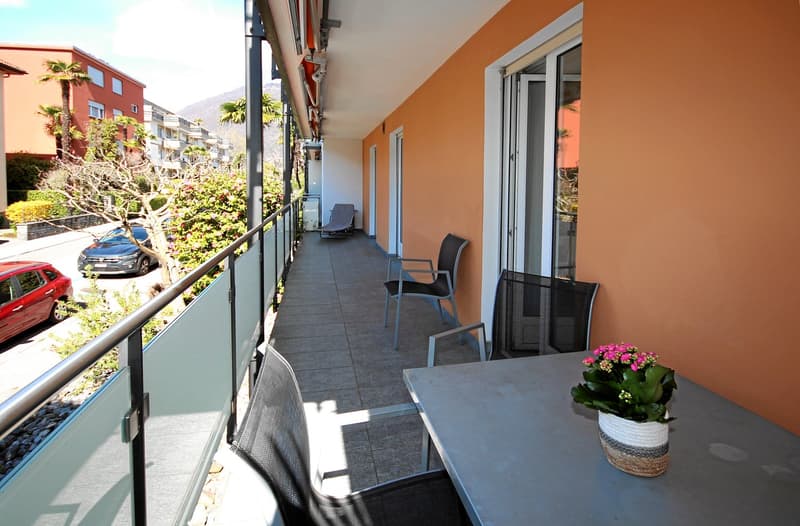 Balcony with chairs, table, flowers, view of the street