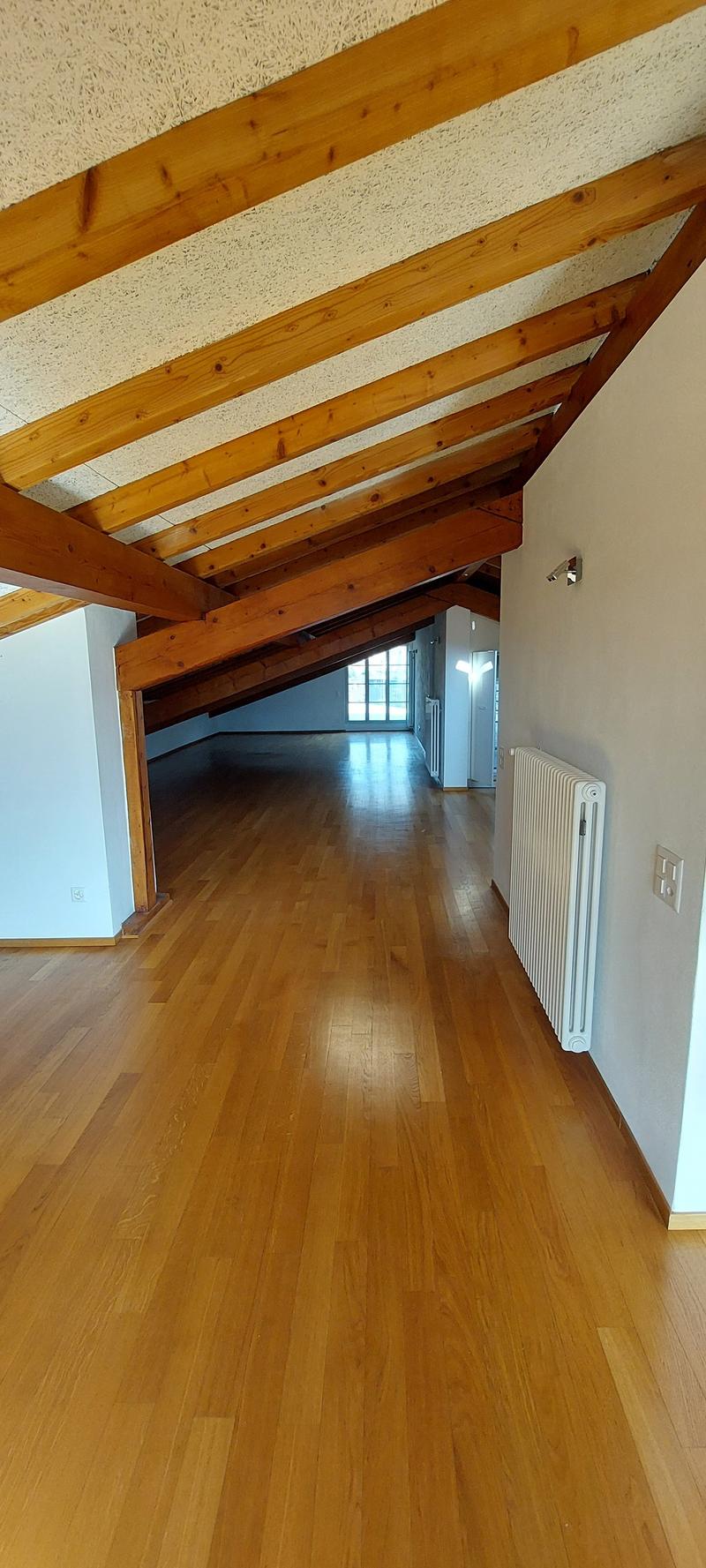 Wooden ceiling, white walls, wooden floor, empty room, window at the end of room