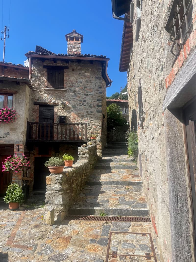 old town stone house, wooden balcony, stone steps, stone pavement, potted plants