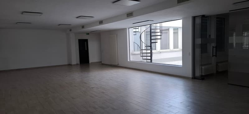Office space with tile floor, white walls, spiral staircase in adjacent room, large windows, a white radiator