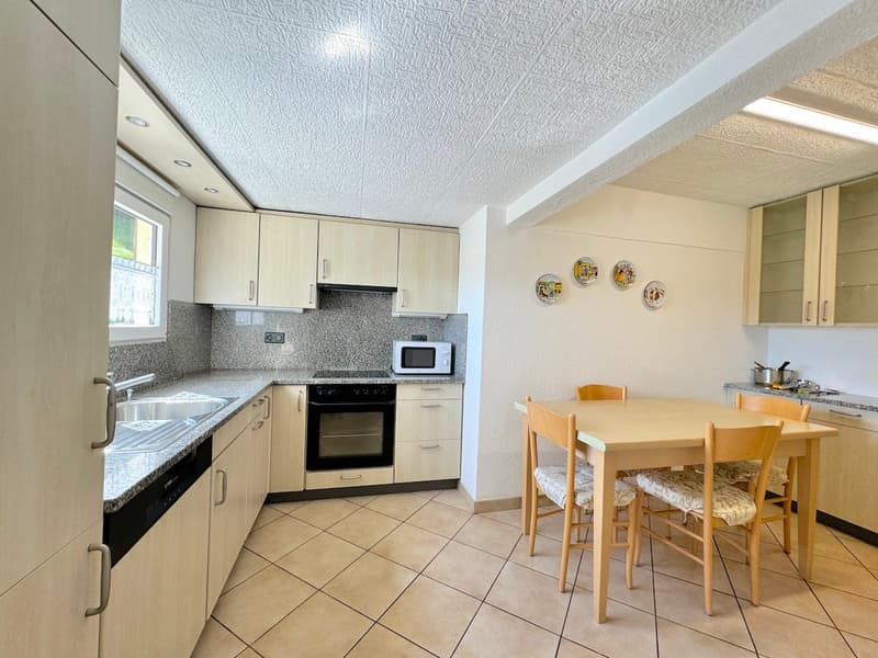 Modern kitchen with wooden countertops, oven, dishwasher, microwave, sink, tiled floor, dining area with table and chairs, cabinets, and hanging decorative plates.
