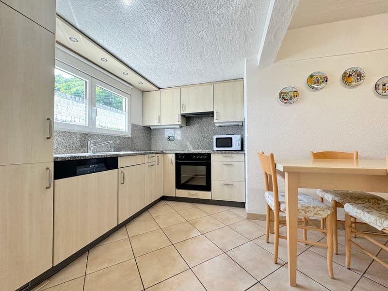 Kitchen area with a microwave, dishwasher, sink, oven, and wooden dining table.
