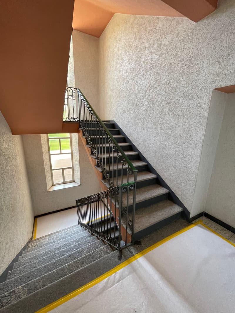 concrete staircase, brown ceiling, white walls, yellow marking on the floor