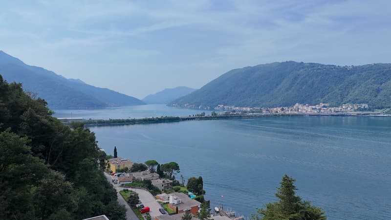 Mountainous landscape with lake and town in distance, multiple buildings