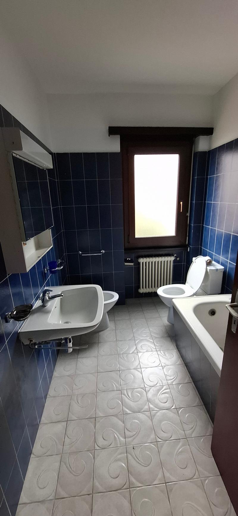 Bathroom with blue tiles, white tiled floor, modern fixtures, white tub, white sink, white toilet