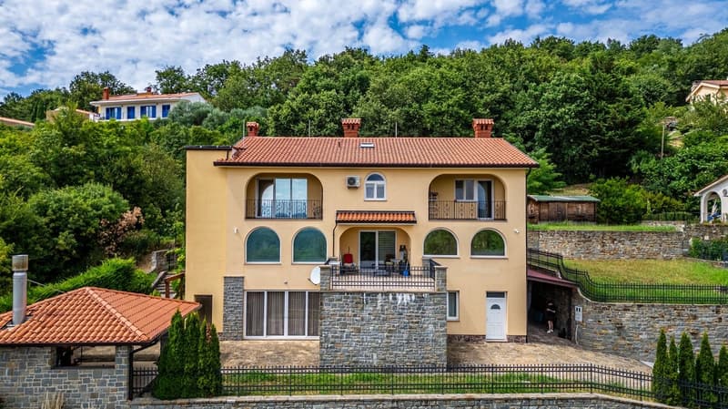 2 story house, yellow exterior, red roof, multiple windows, balcony, stone walls, satellite dish, air conditioner, garden, trees