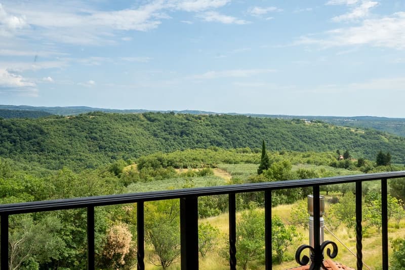 balcony with railing, view of a green valley with trees and hills