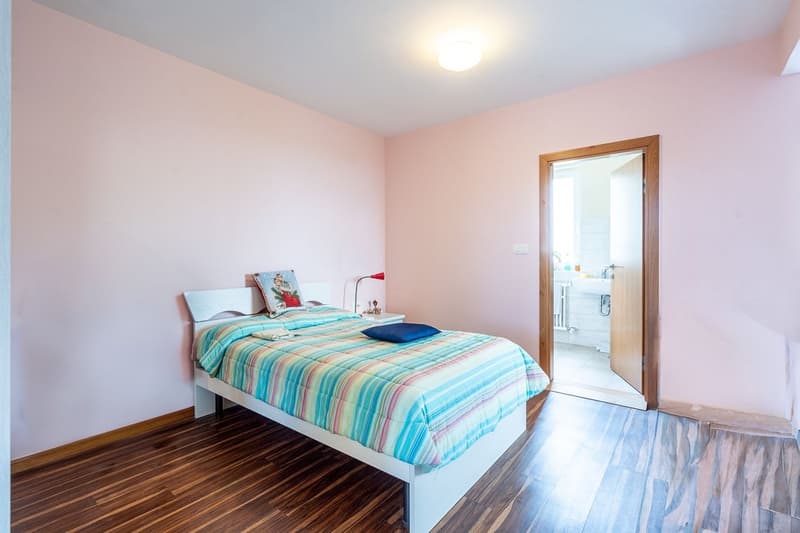 Bedroom with bed, nightstand, lamp, and open door to bathroom