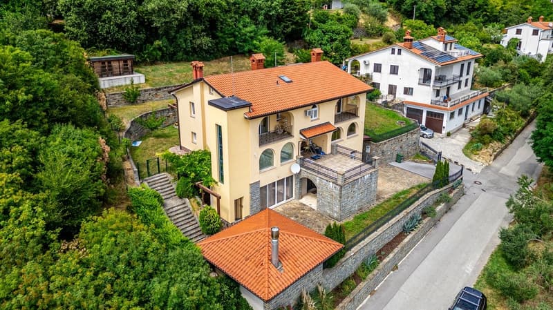 Two story house, red roof, solar panels, balcony, garden, driveway, car parked