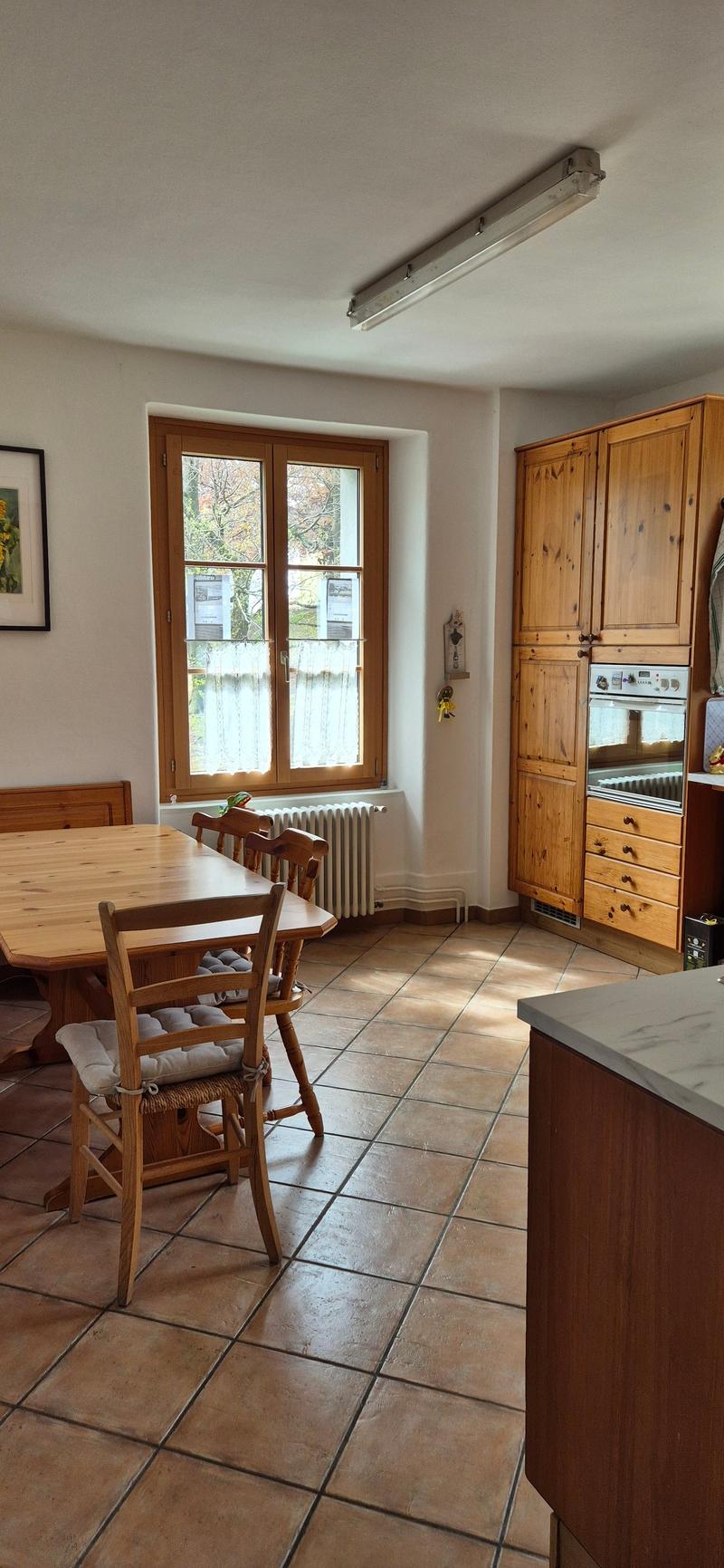 kitchen with dining area, wooden table, chairs, wooden cabinets, window, radiator, oven