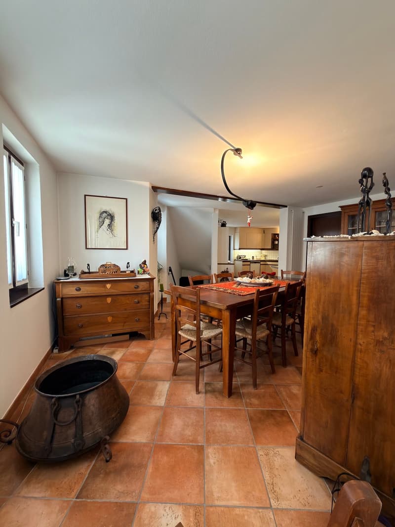 Dining room with wooden table, chairs, wooden cabinet, tiled floor, picture frame, lamp, and a window