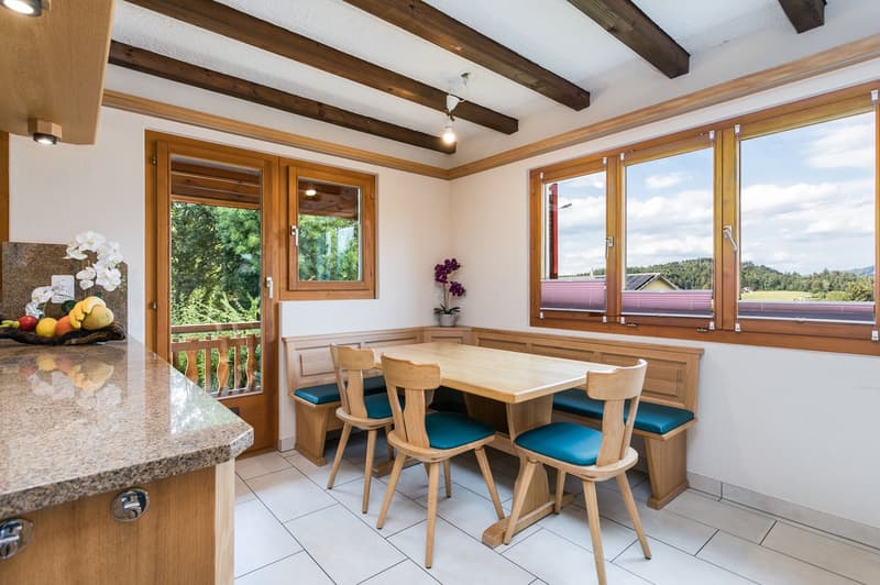 Familienfreundliche Küche mit praktischer Eckbank und passendem Holztisch und links davon Ausgang zum gedeckten Balkon...