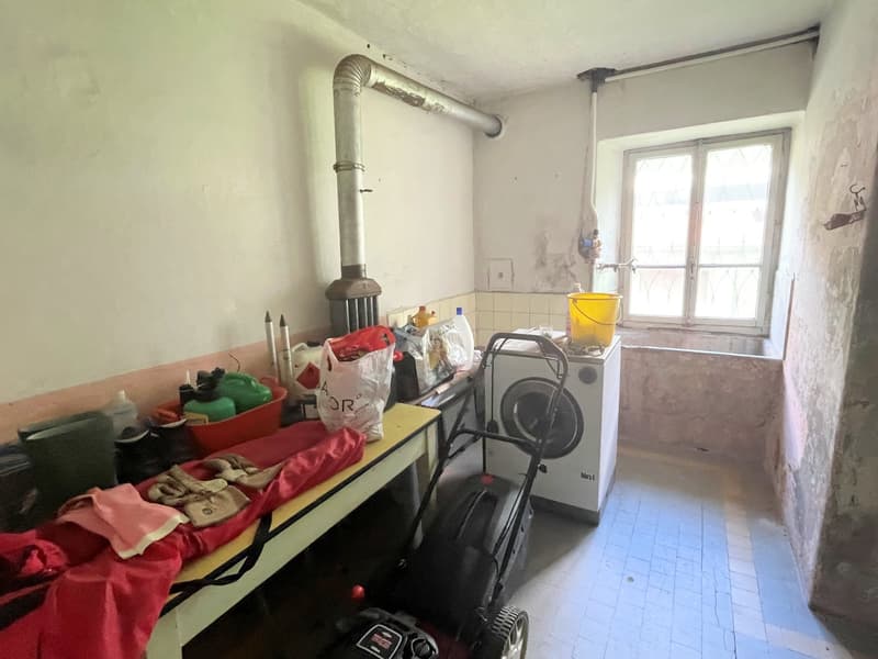 Laundry area with washing machine, buckets, bags, cleaning supplies, and a table