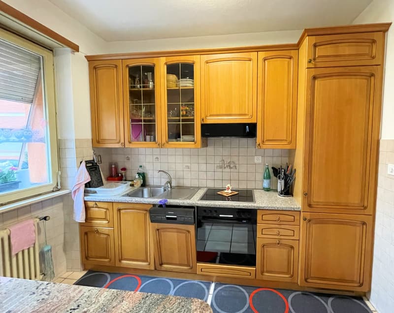 wooden cabinets, double sink, built-in dishwasher, countertop, wooden floor, tiled wall, window