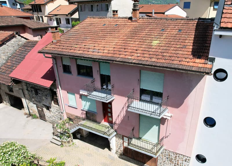 Two story pink house, red roof, multiple balconies