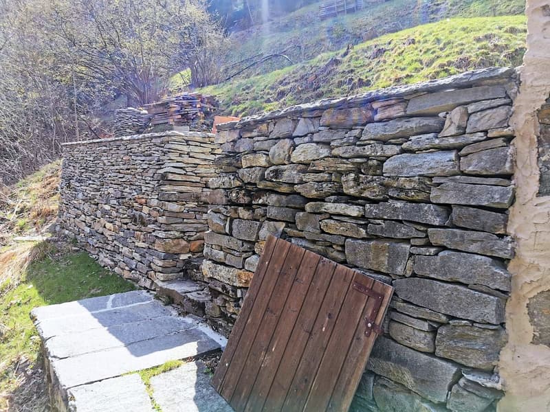 Stone wall in a mountain region with wooden entrance gate